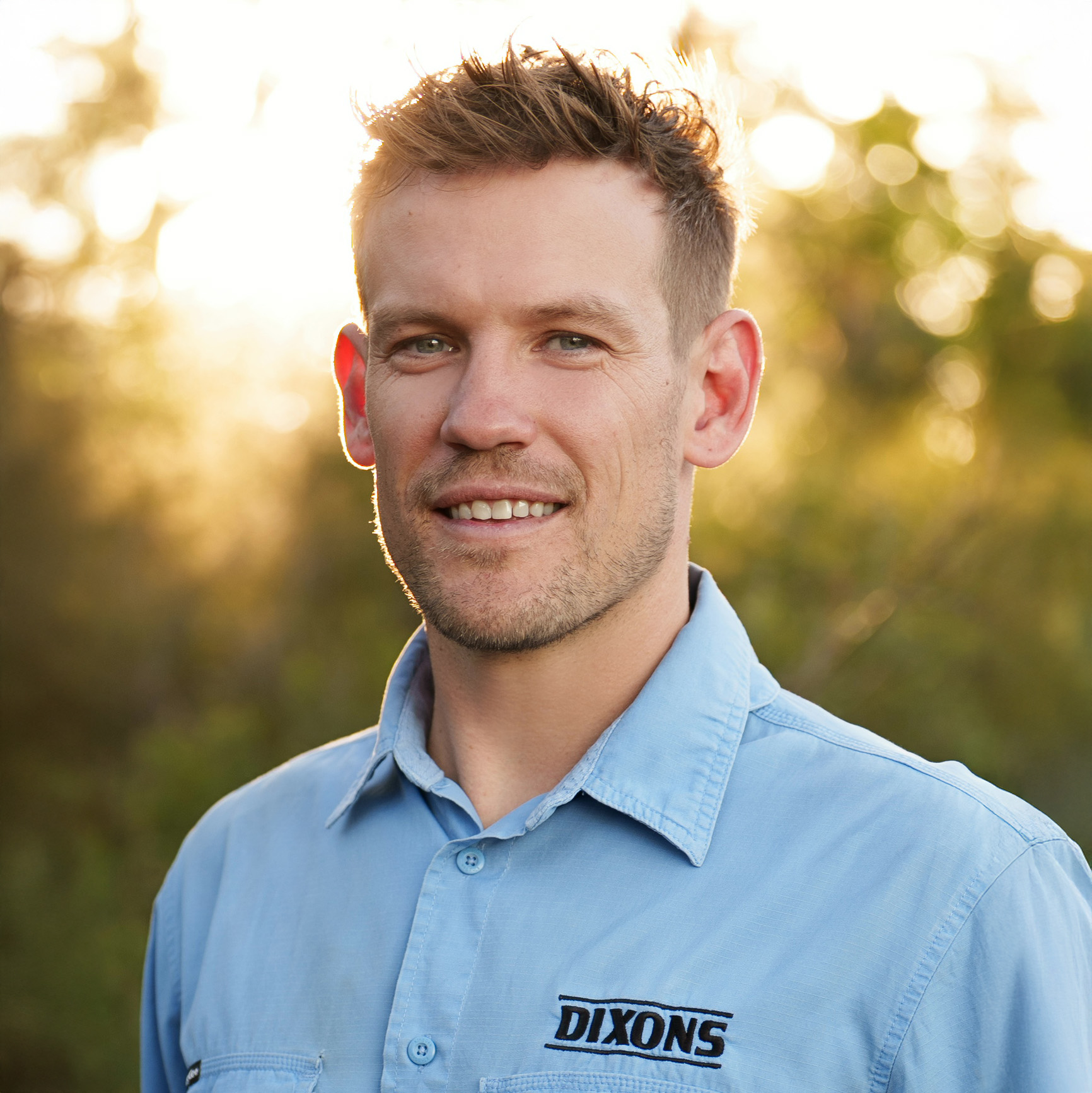 Phil Dixon, professional tree relocation expert, smiling in a blue shirt with greenery in the background, representing reliable tree transplanting services in Sydney, Blue Mountains & South Coast.